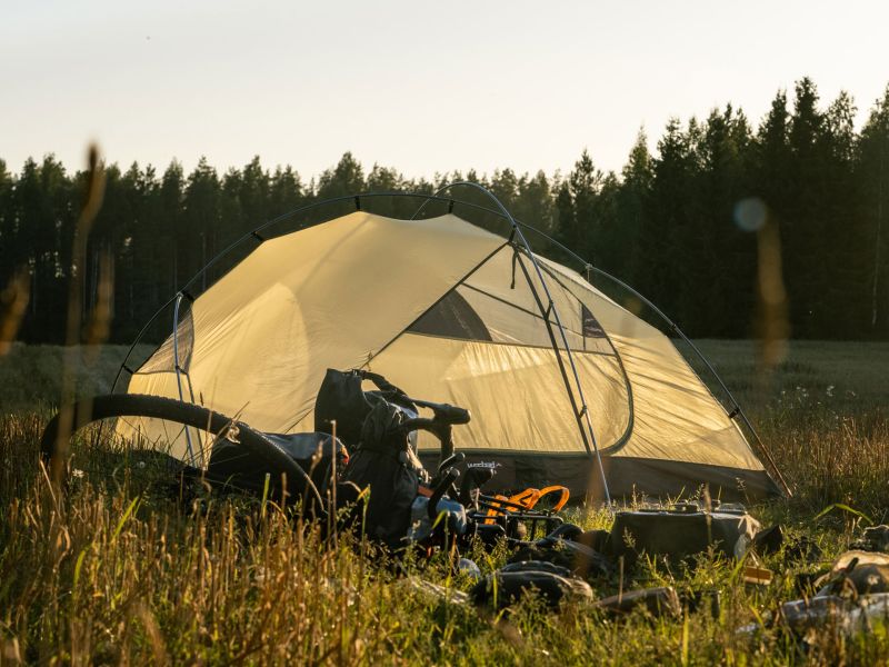 Exogen 3 im Abendlicht auf einer Wiese, davor ein Fahrrad mit Bikepacking-Taschen